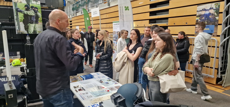 Kriminalistični tehnik med pogovorom z obiskovalci