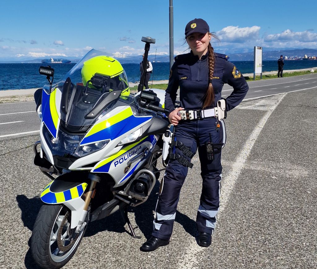 Policistka motoristka s Postaje prometne policije Silvija Peroša stoji ob parkiranem motorju