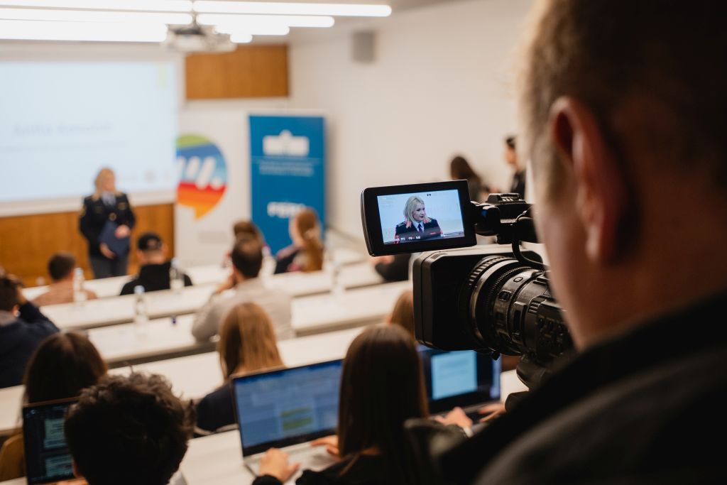 Predstavnica policije predstavlja projekt pred poslušalci v dvorani