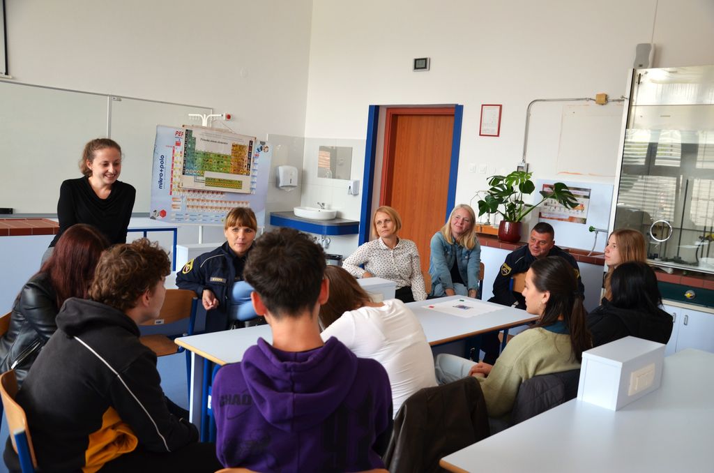 Zbrani v krogu se v učilnici pogovarjajo najstniki, policista, učiteljica in predstavnica centra za socialno delo.