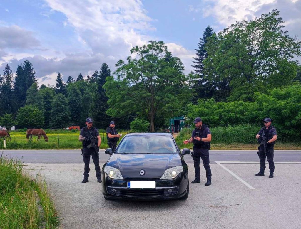 Štirje policisti ob ustavljenem avtomobilu