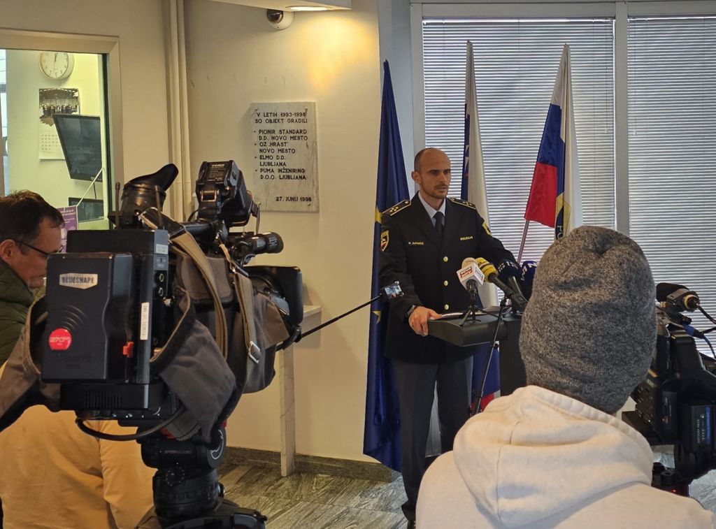 Robert Zupančič stoji za govornico v avli policijske uprave in daje izjavo novinarjem.