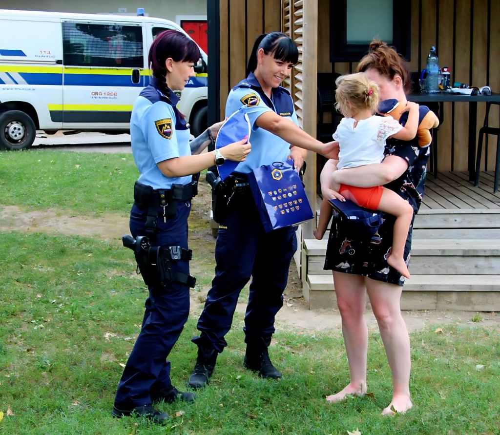 Policistki izročata deklici v materinem naročju darilo