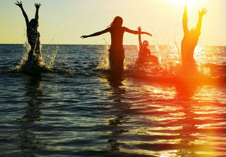 picture of bathers joyfully splashing around in water at sunset