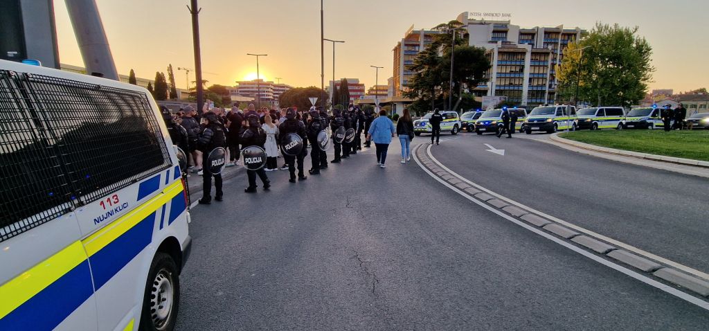Policisti spremljajo odhajanje navijačev s stadiona, v ozadju kolona policijskih vozil