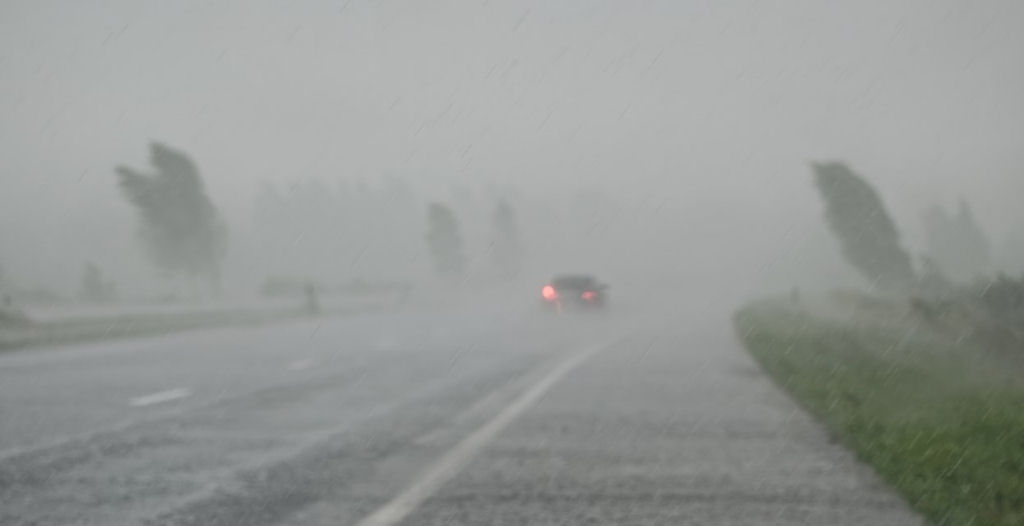 picture of a car driving on the road during a severe storm