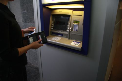 slika osebe, ki se pripravlja za dvig iz bankomata